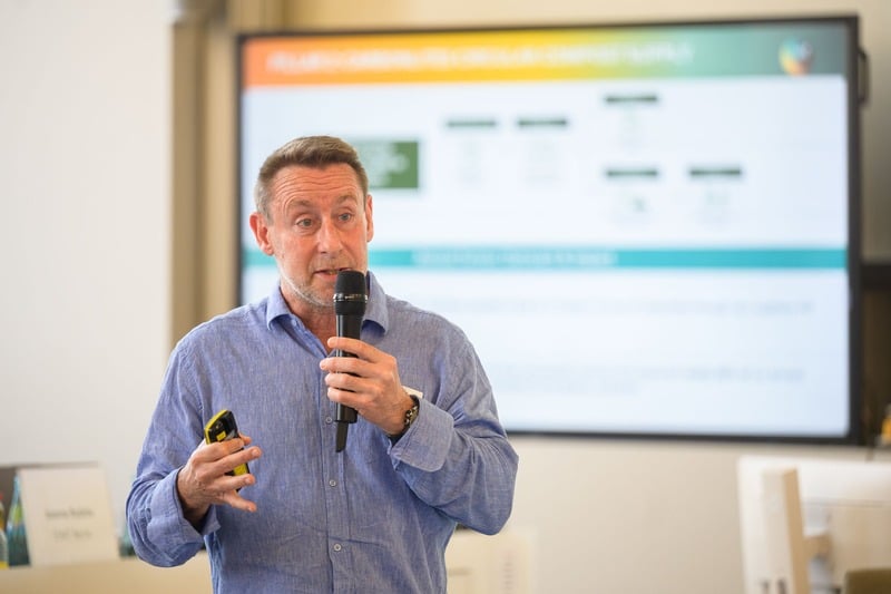 A speaker presenting with a microphone in front of a presentation screen